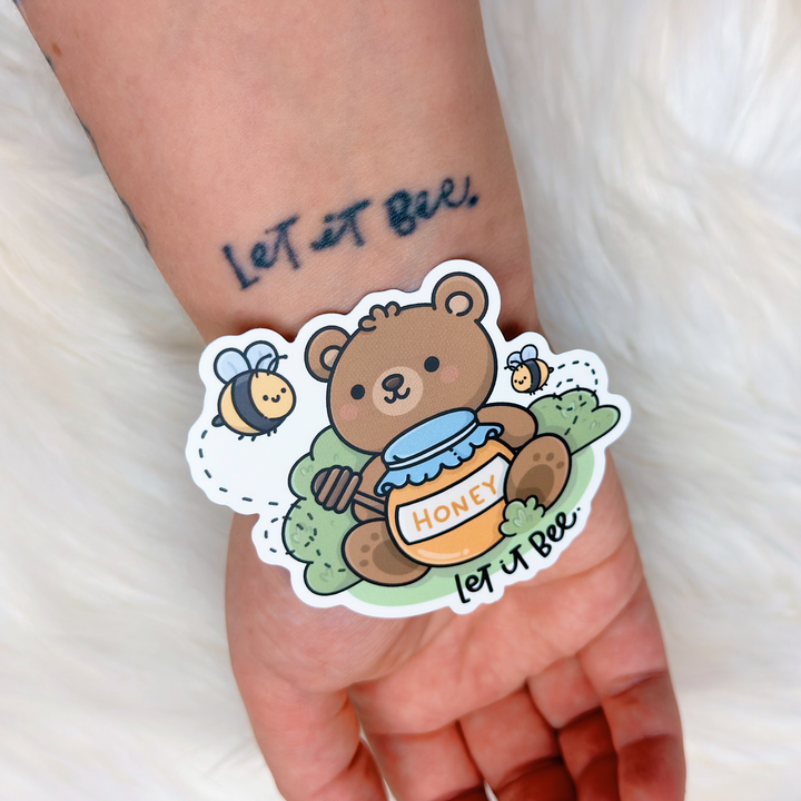 Sticker of a bear holding a honey jar with bees on a wrist, with &