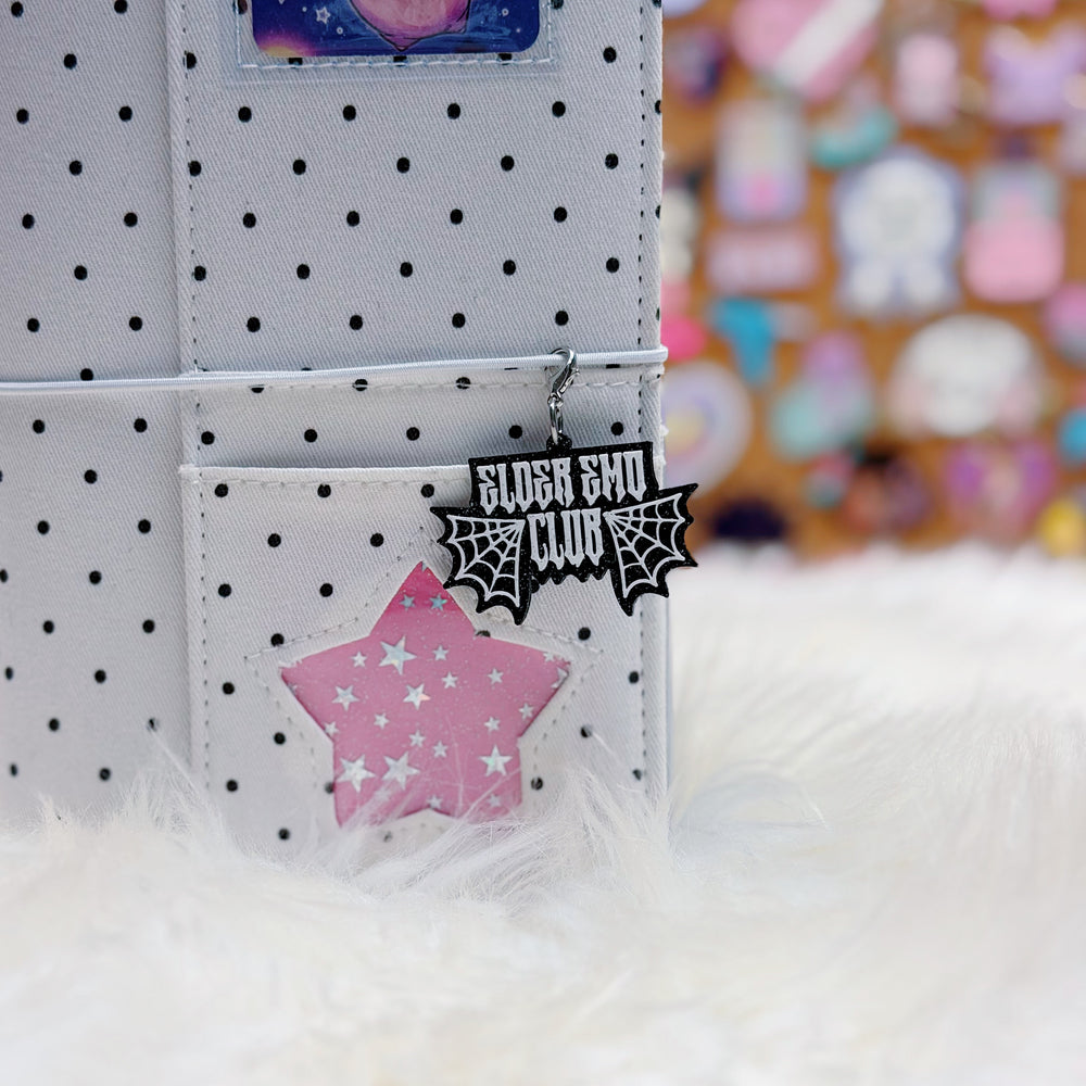 Polka dot bag with a pink star and black spider web design tag on a white surface.