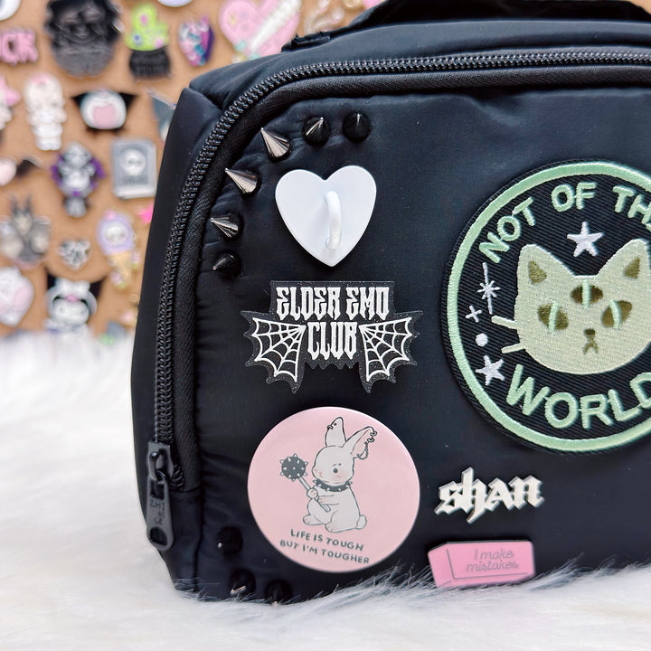 Black bag with various patches and stickers on a white surface