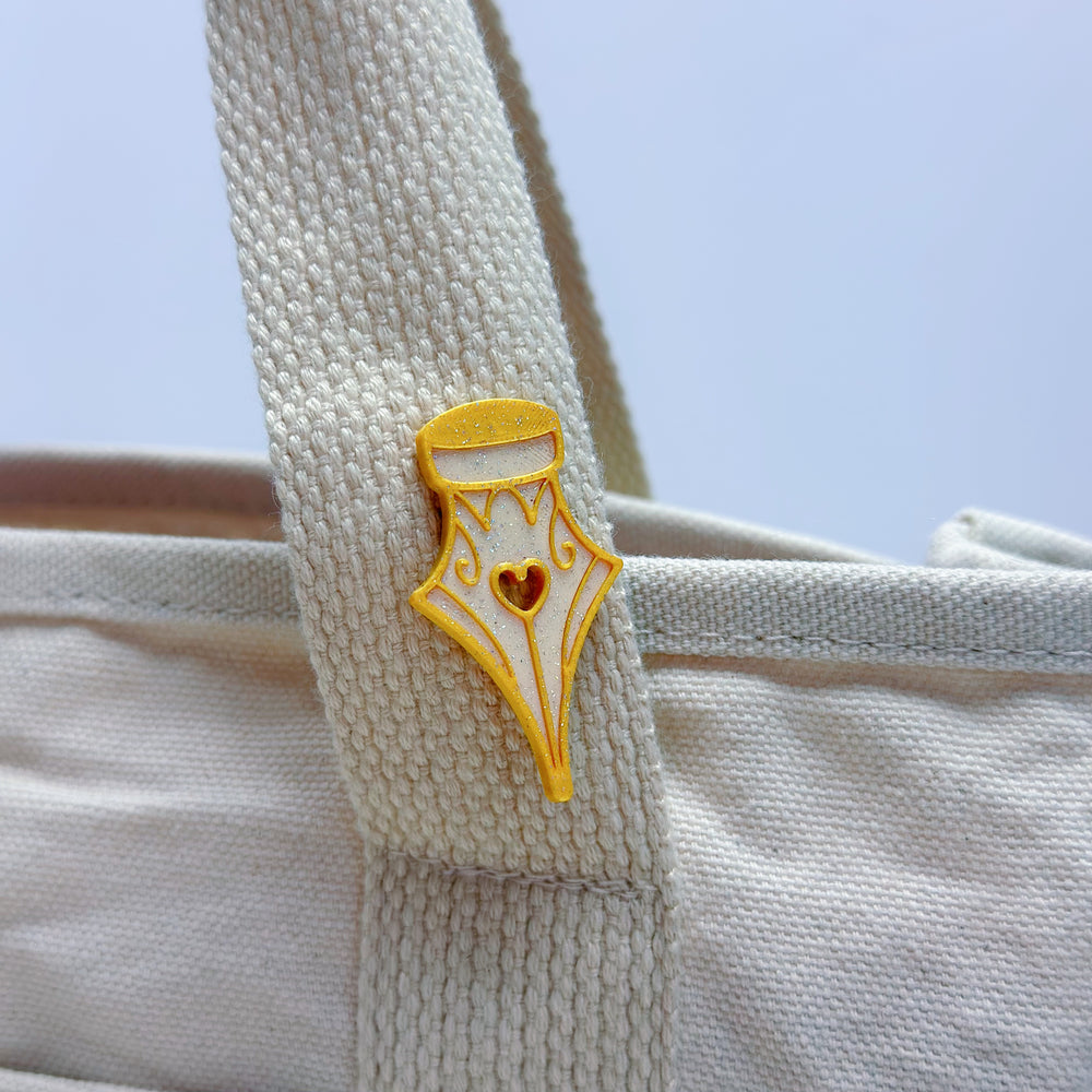 Yellow and white decorative pin on a textured beige surface with a light blue background