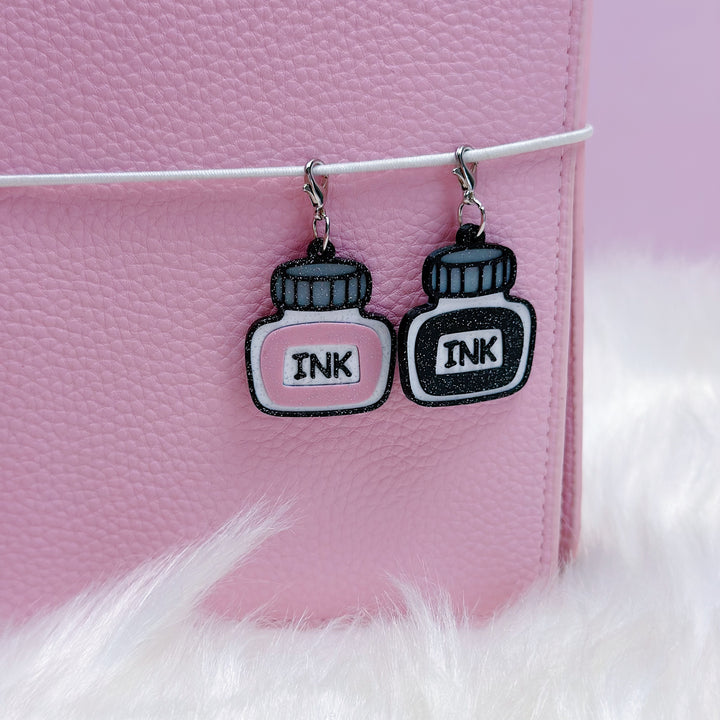Ink bottle earrings on a pink background