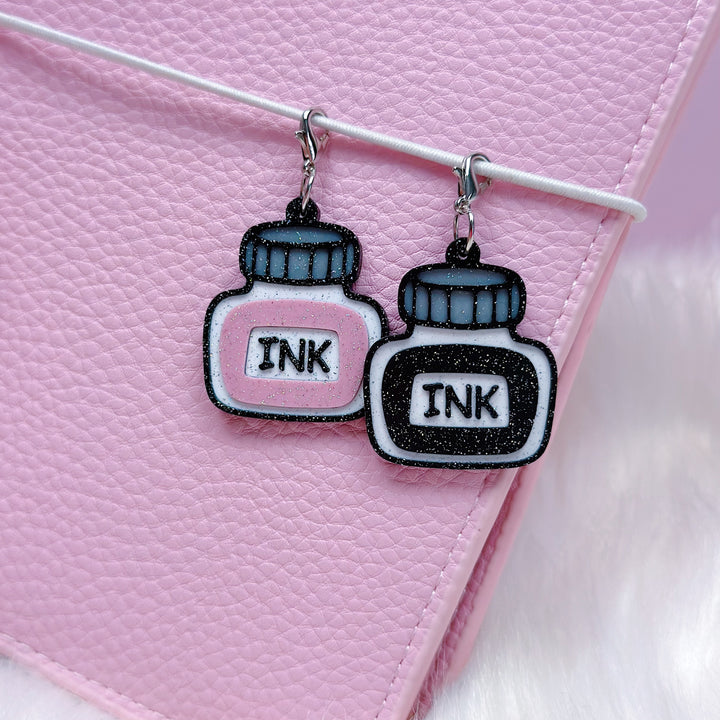 Ink bottle earrings on a pink background