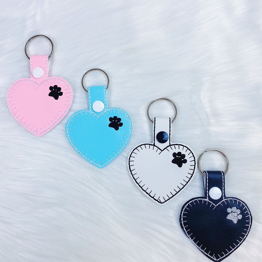 Charm con lengüeta a presión de fieltro de corazón con estampado de pata blanca